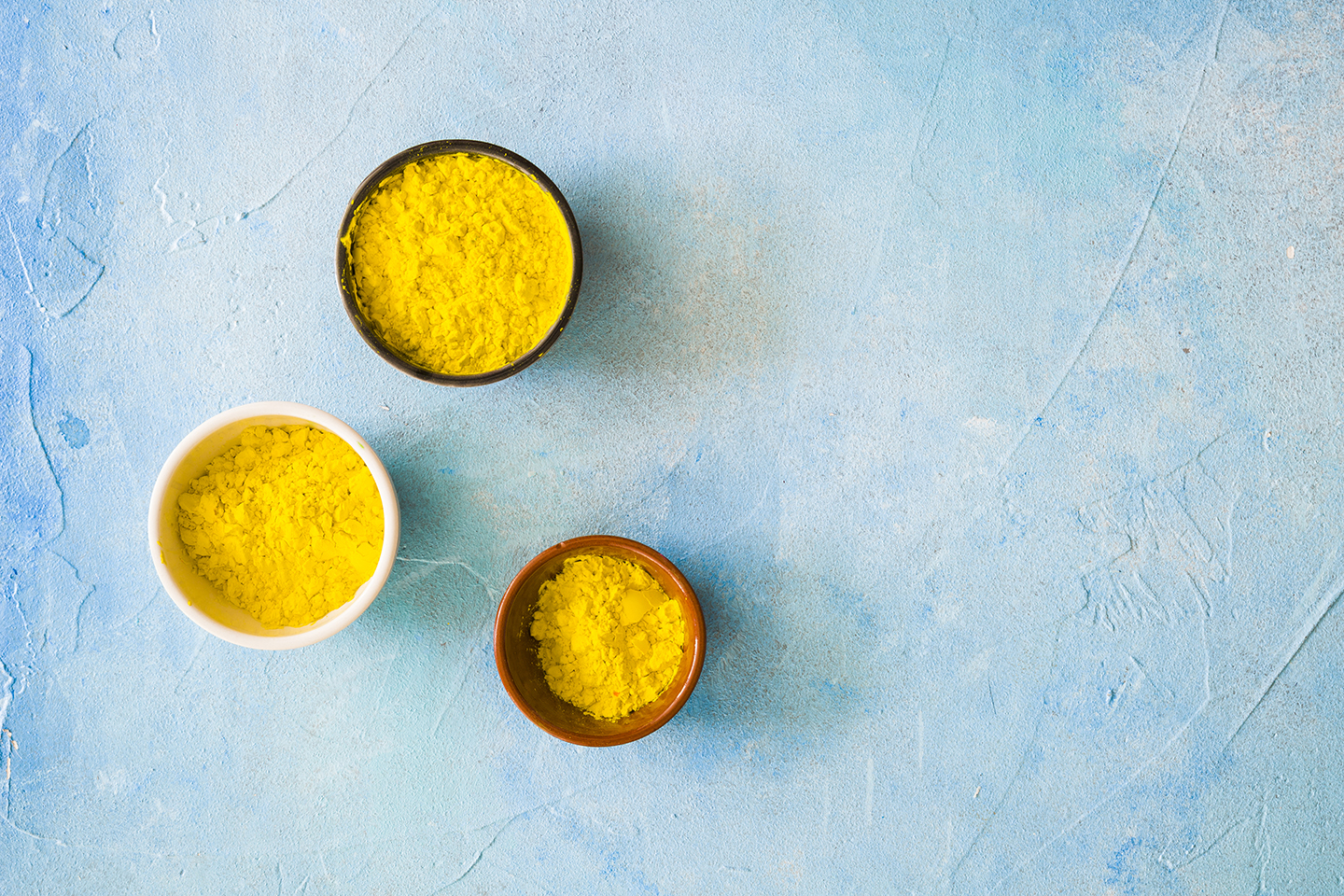 yellow-holi-color-powder-different-type-bowls-blue-painted-backdrop.jpg